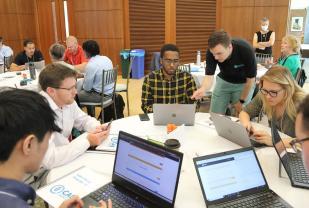 group of students around table with computers