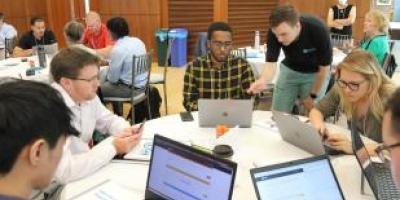 group of students around table with computers