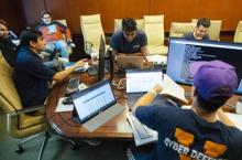 Group of cyber defense team members working at table together